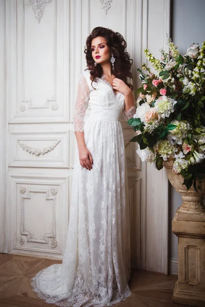 Gros plan portrait de magnifique belle mariée en robe blanche avec une coiffure étonnante et le maquillage, tenant bouquet — Photo