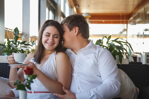 Hezká mladá bruneta žena v bílých šatech a mladý muž odpočívající společně v restauraci v letní den — Stock fotografie