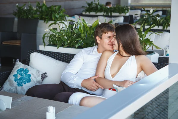 Ganska ung brunett kvinna i vit klänning och en ung man vila tillsammans på en restaurang i en sommardag — Stockfoto