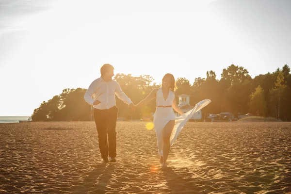 Hermosa pareja hombre y mujer descansa juntos en una playa en una noche de verano — Foto de Stock