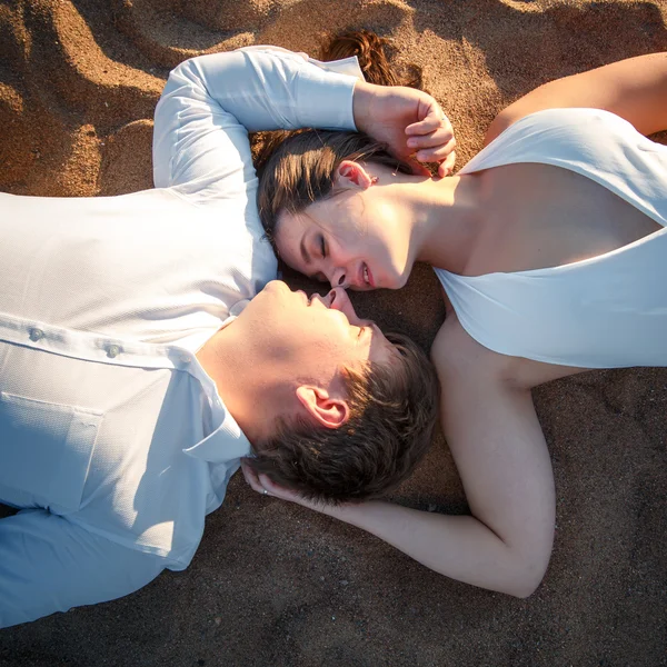 Hermosa pareja hombre y mujer descansa juntos en una playa en una noche de verano — Foto de Stock