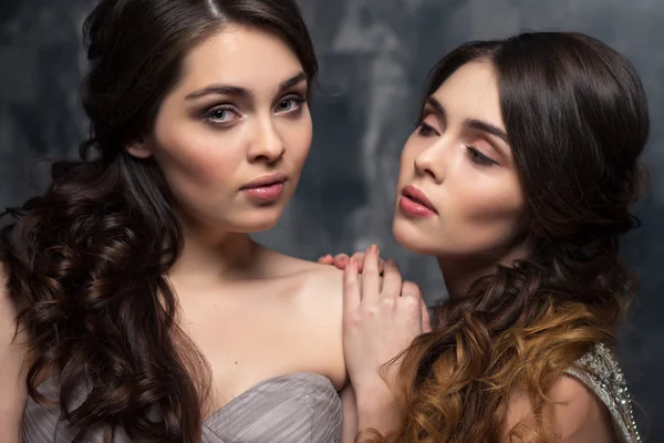 Fashion beauty ritratto di bellissime giovani gemelle donne con lunghi capelli ricci in abiti da sera di lusso — Foto Stock