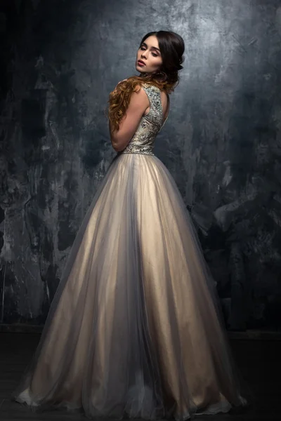 豪華なイブニング ドレスの長い巻き毛を持つ豪華な若い女性のファッションの美しさの肖像画 ロイヤリティフリーのストック写真
