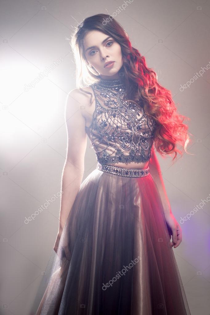 Fashion beauty portrait of gorgeous young woman with long curly hair in luxury evening dress