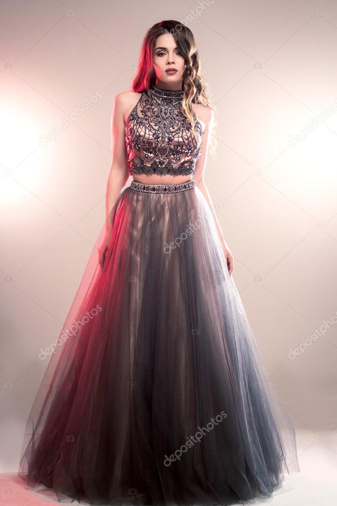 Fashion beauty portrait of gorgeous young woman with long curly hair in luxury evening dress