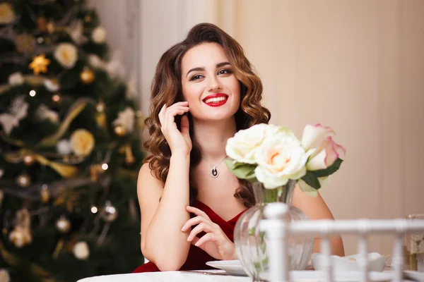 Close-up retrato de bela jovem mulher em lindo vestido de noite de veludo vermelho sentado à mesa no interior caro — Fotografia de Stock
