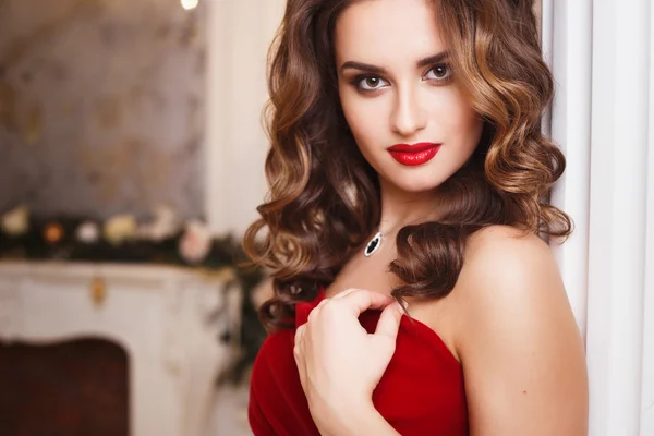 Gyönyörű fiatal nő, a tökéletes smink és frizura, gyönyörű piros estélyi ruhában, a drága luxus belső — Stock Fotó