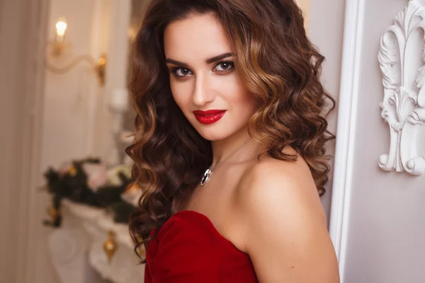 Krásná mladá žena s perfektním make-upu a účesu v nádherné červené večerní šaty v drahé luxusní interiér — Stock fotografie