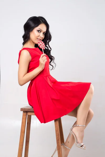Csinos, fiatal nő, piros ruhás egy nyalóka — Stock Fotó