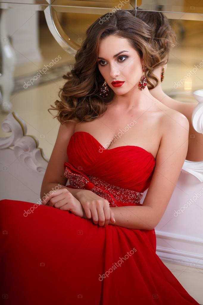 Beautiful young woman with perfect make up and hair style in gorgeous red evening  dress in expensive luxury interior Stock Photo by ©cherry_daria 95739616