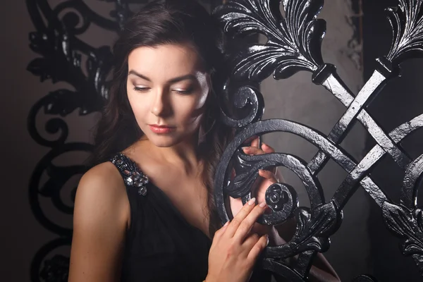 Портрет елегантної молодої брюнетки в чорній довгій вечірній сукні в інтер'єрі — стокове фото