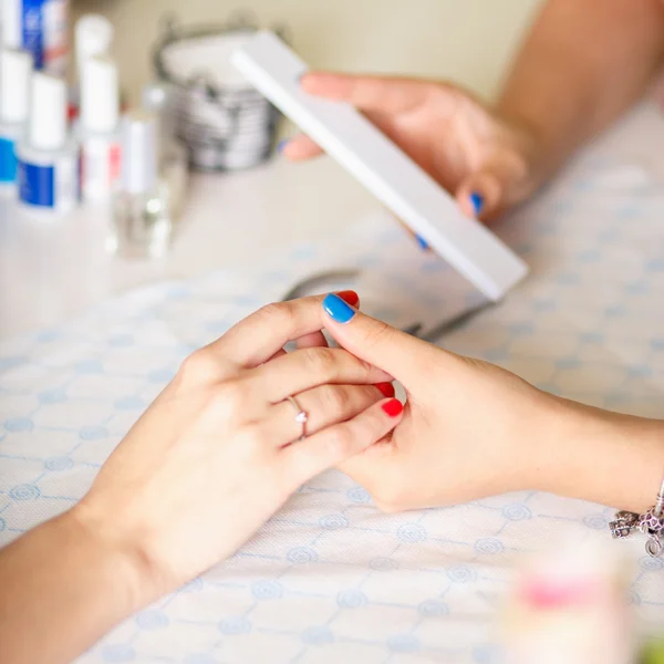 Primer plano de una mujer en un salón de belleza recibiendo una manicura por un esteticista con lima de uñas. Mujer haciéndose manicura de uñas. Lima de esteticista uñas a un cliente . — Foto de Stock