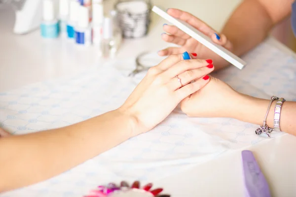 Primer plano de una mujer en un salón de belleza recibiendo una manicura por un esteticista con lima de uñas. Mujer haciéndose manicura de uñas. Lima de esteticista uñas a un cliente . — Foto de Stock