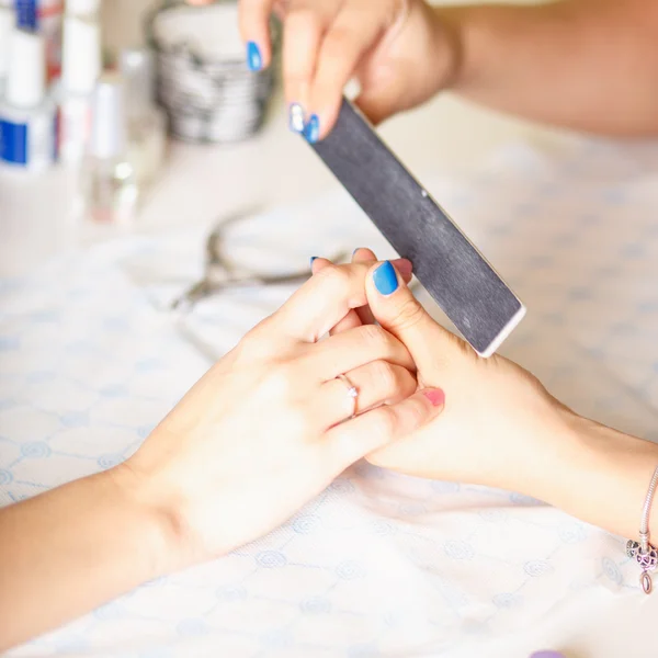 Syuting closeup seorang wanita di salon kuku menerima manikur oleh seorang ahli kecantikan dengan file kuku. Wanita mendapatkan manikur kuku. File kuku Beautician untuk pelanggan . — Stok Foto