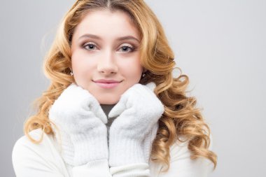 close-up portrait of a blonde girl in a warm white pullover isolated on white background
