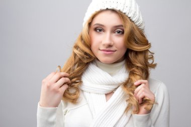 close-up portrait of a blonde girl in a warm white pullover and hat isolated on white background