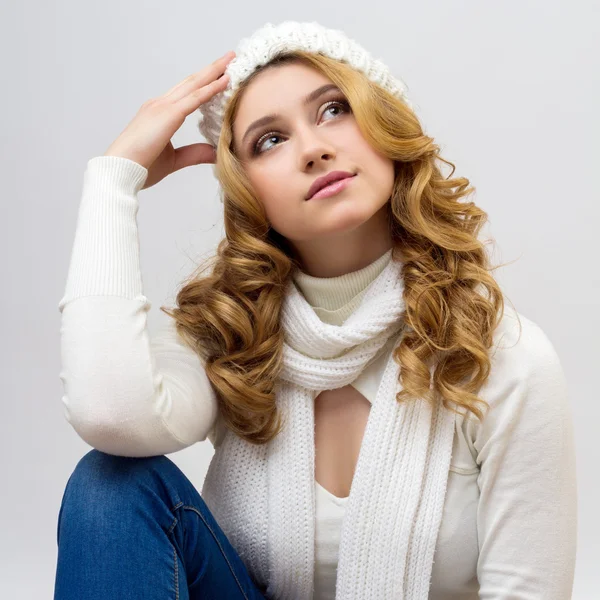 Close-up portrait of a blonde girl in a warm white pullover and hat isolated on white background — 图库照片