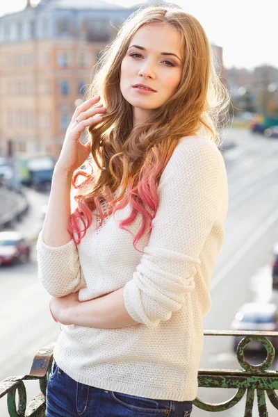 Portrait of young lady wearing white pullover posing on a balcony — Zdjęcie stockowe