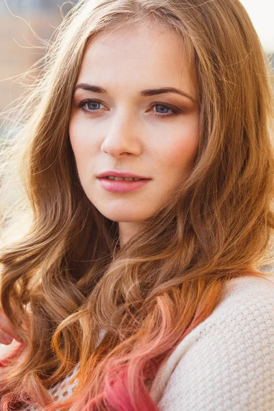 Portrait of young lady wearing white pullover posing on a balcony — Stockfoto