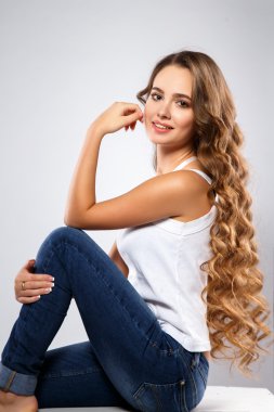Close-up portrait of beautiful young woman with gorgeous hair and natural makeup wearing casual clothes. Fashion beauty photo, casual jeans style