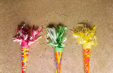 2021 yılını kutlayan konfetilerle parti trompetleri. Parlak altın arka planda renkli parti boynuzları.