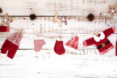 Ren geyiklerinin minimalist Noel çelengi Noel Baba kıyafetleri ve beyaz ahşap arka planda çam kozalakları. Yeni yıl ve Noel konsepti.