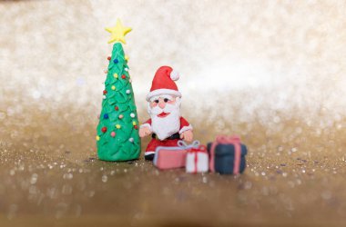 Oyuncak killi noel konsepti. Renkli el yapımı minyatür Noel Baba ve altın kaplama hediyeler.