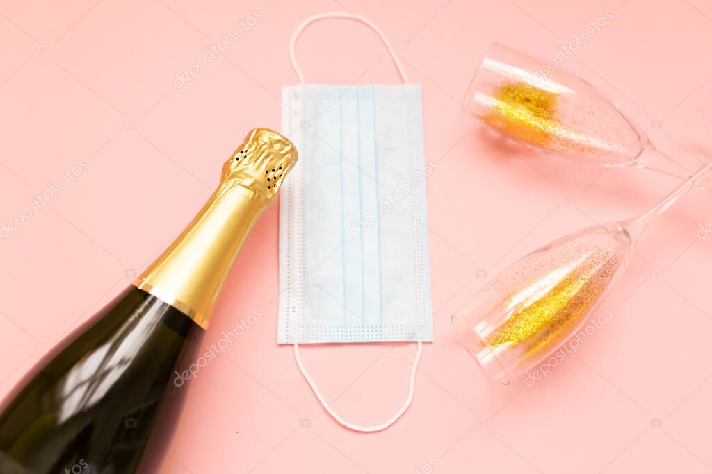 Bottle of champagne face mask and glasses with gold glitter on pink background. Party decor. Christmas, birthday or wedding concept. Flat lay. Festive, drink. New year 2021 celebration.