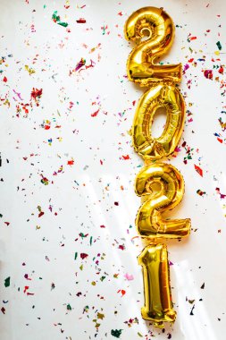 Altın folyo balonları 2021 numaralı beyaz arka planda renkli konfeti ile. Mutlu yıllar 2021 kutlamaları..