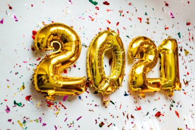 Altın folyo balonları 2021 numaralı beyaz arka planda renkli konfeti ile. Mutlu yıllar 2021 kutlamaları..