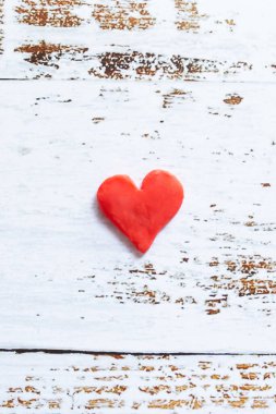 Beyaz ahşap zemin üzerinde plastik kırmızı kalp.
