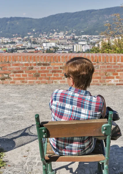 Kvinna sitter på parkbänk med Graz stadsbilden, Österrike — Stockfoto