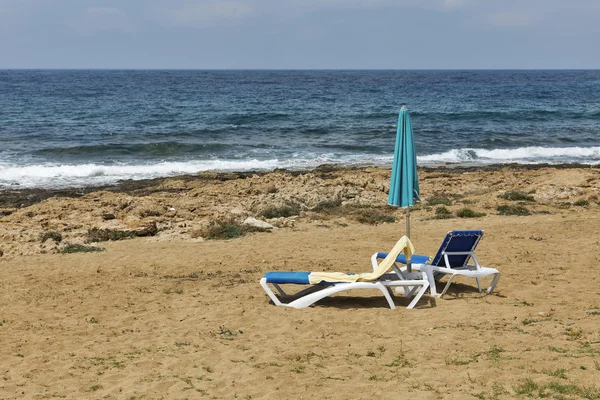 Tumbonas y sombrilla para relajarse en la playa de mar —  Fotos de Stock