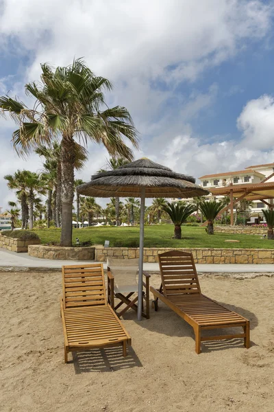 Camas de sol e guarda-chuva de palha para relaxar na praia do mar — Fotografia de Stock