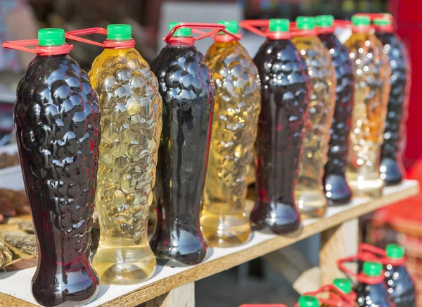 Home brewed wine in plastic bottles on sale in street market — Stock Photo, Image