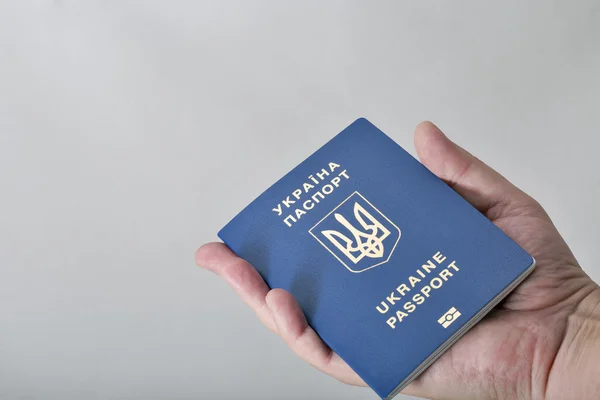 Mão segurando passaporte biométrico ucraniano no fundo branco — Fotografia de Stock