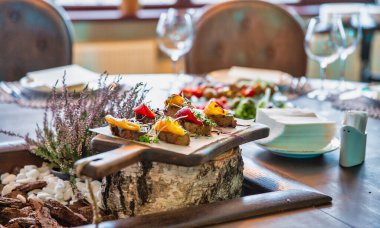 Biberli bruschetta ve mikroyeşiller yakın plandaki bir restoranın masasında, ahşap bir tahtanın üzerinde servis ediliyor.