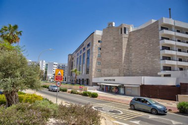 AYIA NAPA, CYPRUS - 22 Mayıs 2021: Yaz boyunca güneşli Nissi Bulvarı ve şehir merkezindeki Adams Beach Oteli boyunca insanlar dolaşır. Ayia Napa, Kıbrıs 'ın güney sahilinin doğu ucunda bir turizm beldesi..