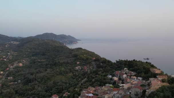 日没時に西海岸とペレカス村の上空からの空中ドローンの眺め ギリシャのコルフ島 — ストック動画