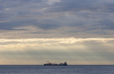 Kargo gemisi günbatımında taş yüklü