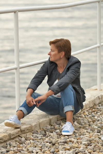 海のビーチに座っている中年の白人女性 — ストック写真