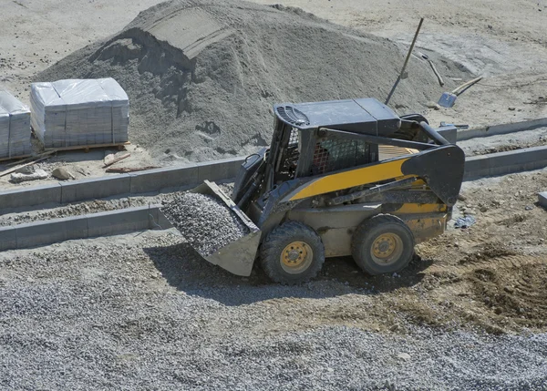 Kleine bulldozer loader breakstone rijdt met Bouwoppervlakte — Stockfoto