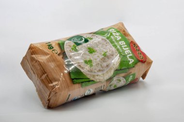 Porec, Hırvatistan - 24 Mayıs 2025: Uzun tahıllı beyaz pirinç paketi ve yeşil etiketli pirinç maydanozla süslenmiş, kahverengi kağıt ambalaja sarılı beyaz arka planda.