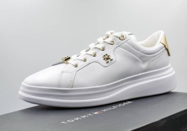 Kyiv, Ukrayna - 02 Mart 2025: Siyah markalı ayakkabı kutusuna yerleştirilmiş altın aksanlı beyaz deri Tommy Hilfiger spor ayakkabıları. Metal donanım ve dantel kaplama içeren klasik düşük-üst tasarım.