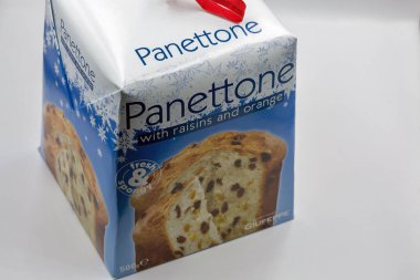 Kyiv, Ukrayna - 21 Aralık 2024: Kuru üzüm ve turuncu aromalı kutulu İtalyan panettonu, kırmızı kurdele saplı bayram mavisi ambalaja sarılmış, beyaz arka plan kapağında sergilenmektedir..