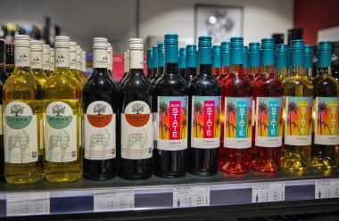 Kyiv, Ukrayna - 25 Ekim 2025: Modern bir şarap dükkanının perakende rafında çeşitli kırmızı, beyaz ve gül şarap şişeleri sergilenmektedir. Çağdaş alkol mağazasının içindeki markalı etiketler.