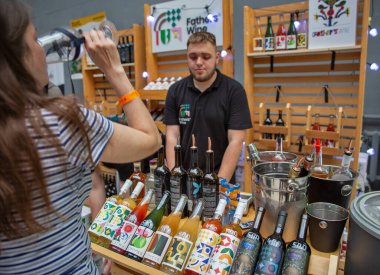 Kyiv, Ukrayna - 7 Haziran 2025: Ziyaretçiler Yemek ve Şarap Festivali sırasında Baba Şarap standında şarap tadıyorlar. Renkli etiketli şişeler satıcı misafirlere hizmet ederken sergilenir.