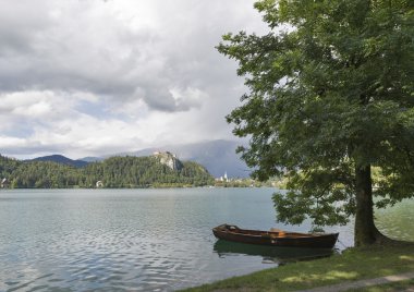 Lake Bled üzerinde ağaç gölgede tekne palamarla.