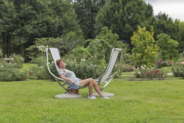 Mulher branca sentada na frente do jardim de rosas — Fotografia de Stock