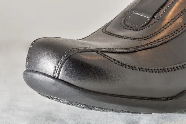 Black man leather toe of a boot on white closeup